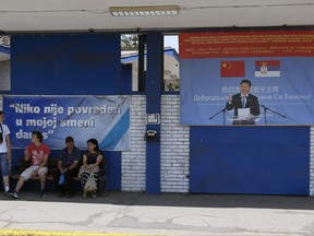In this photo taken Thursday, June 29, 2017, workers rest near billboard showing Chinese President Xi Jinping, reading: "Welcome President", right, and billboard reading: "Nobody was hurt in my shift today" in front of the Zelezara Smederevo steel mill, in the city of Smederevo, 45 kilometers east of Belgrade, Serbia. When U.S. Steel sold its loss-making smelter in Serbia to the government for $1 in 2012, few thought the communist-era factory would ever be revived. Then came along a state-owned Chinese company. Hebei Iron & Steel's 46 million-euro ($52 million) purchase of the steelworks last year is part of China's broader effort to project influence and gain access to the European market as other traditional powers, particularly the U.S. under President Donald Trump, retreat from the world stage. (AP Photo/Darko Vojinovic)
