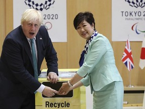 Britain's Foreign Secretary Boris Johnson, left, and Tokyo Gov. Yuriko Koike, right, tosses an unused mobile phone in to a recycle bin prior to their meeting at the Tokyo Metropolitan government office in Tokyo Friday, July 21, 2017. Organizers of the 2020 Tokyo Olympics collect discarded electronic devices that will be used in the production of the medals to be awarded to athletes. (AP Photo/Eugene Hoshiko)