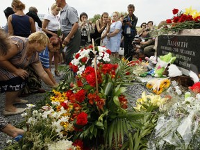 Local residents lay flowers to commemorate victims of the Malaysian Airlines plane, near the village of Hrabove, Donetsk region, eastern Ukraine, Monday, July 17, 2017.  Relatives and friends of people killed three years ago when a surface-to-air missile blew a Malaysia Airlines passenger jet out of the sky over Ukraine gathered Monday to mark the anniversary at a new memorial near the Amsterdam airport from which the plane departed. (AP Photo/Olexander Ermochenko)