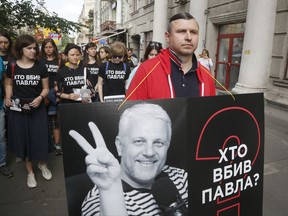 Activists and journalist march to pay tribute to murdered journalist Pavel Sheremet, wearing T-shirts that read "Who killed Pavel?", in Kiev, Ukraine, Thursday, July 20, 2017. Sheremet, 44, was killed in Kiev in a car explosion last year. Despite promises from President Petro Poroshenko to solve the case, no progress is visible a year after the killing and Ukrainian journalists say the inaction leaves them feeling increasingly imperiled. (AP Photo/Efrem Lukatsky)