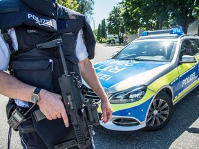 A policeman guards at a road near a school in Esslingen, Germany, Monday, July 17, 2017. Police said a suspect wanted after he showed up with a firearm at a high school in southwestern Germany on Monday was still on the loose because they initially arrested the wrong man. Police tweeted that the man they arrested was let go again and that the suspect had probably fled on a motor bike.  (Sven Friebe/dpa via AP)