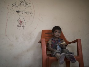 A boy sits next to a defaced drawing of the Islamic State flag while waiting in a house to be taken out of the Old City during fighting between Iraqi forces and Islamic State militants, in Mosul, Iraq, Sunday, July 9, 2017.