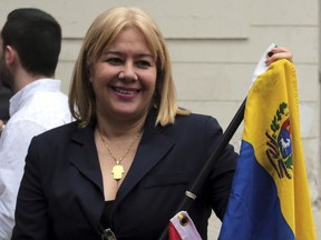 In this July 21, 2017 photo, newly-appointed Supreme Court justice Zuleima Gonzalez holds a Venezuelan flag as she poses for photos after her swearing-in ceremony in Caracas, Venezuela. Gonzalez, one of 33 of magistrates appointed by the opposition-led National Assembly last week, was detained by political police (SEBIN), along with another judge, on suspicion of treason, in eastern Venezuela, according to the legislature on July 25, 2017. (AP Photo/Fernando Llano)