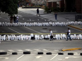 Pedestrians walk past a barricade set up by demonstrators during a 48-hour general strike beginning Wednesday in protest of government plans of Venezuela's President Nicolas Maduro to rewrite the constitution, in Caracas, Venezuela, Wednesday, July 26, 2017. Opposition leader Leopoldo Lopez called on Venezuelans to support the general strike, in his first direct public message since being released from prison to house arrest. (AP Photo/Ariana Cubillos)