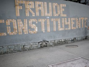 A pedestrian walks next to a message on a wall formed with Venezuelan currency that reads in Spanish: "The Constituent Assembly is a fraud", in Caracas, Venezuela, Monday, July 31, 2017. Electoral authorities said more than 8 million people voted Sunday to create a constitutional assembly endowing President Nicolas Maduro's ruling party with virtually unlimited powers - a figure widely disputed by independent analysts. (AP Photo/Ariana Cubillos)