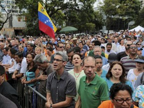 People sing Venezuela's national anthem at a swearing-in ceremony for newly named Supreme Court justices, in Caracas, Venezuela, Friday, July 21, 2017. Venezuela's opposition-led National Assembly has sworn in new magistrates to the government-dominated Supreme Court during a ceremony held in a public plaza. The naming of the new justices is part of the opposition's plan to resist President Nicolas Maduro's efforts to rewrite the constitution. (AP Photo/Fernando Llano)