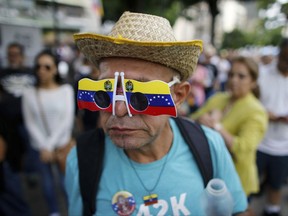 A man wearing a sunglasses with the colors of the Venezuelan flag lineup prior cast his ballot at a poll station during a symbolic referendum in Caracas, Venezuela, Sunday, July 16, 2017. Venezuela's opposition called for a massive turnout Sunday in a symbolic rejection of President Nicolas Maduro's plan to rewrite the constitution, a proposal that's escalating tensions in a nation stricken by widespread shortages and more than 100 days of anti-government protests. (AP Photo/Ariana Cubillos)