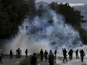 Demonstrators walk amid tear gas fired by Bolivarian National Guards during clashes in the El Hatillo neighborhood on the outskirts of Caracas, Venezuela, Thursday, July 20, 2017. Venezuelan President Nicolas Maduro and his opponents face a crucial showdown Thursday as the country's opposition calls a 24-hour national strike. (AP Photo/Fernando Llano)