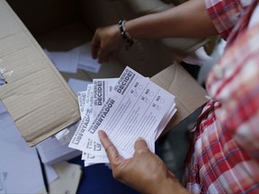 Volunteers count the ballots after the poll station closed during a symbolic referendum in Caracas, Venezuela, Sunday, July 16, 2017. Venezuela's opposition called for a massive turnout Sunday in a symbolic rejection of President Nicolas Maduro's plan to rewrite the constitution, a proposal that's escalating tensions in a nation stricken by widespread shortages and more than 100 days of anti-government protests. (AP Photo/Ariana Cubillos)