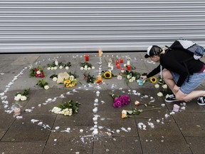 A woman places flowers  near a supermarket in Hamburg, Germany,  Saturday, July 29, 2017. A man armed with a kitchen knife fatally stabbed one person at athe supermarket Friday in the northern German city of Hamburg and six others were injured as he fled, police said. He was overpowered and arrested. (Markus Scholz/dpa via AP)