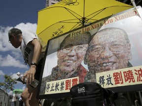 A protester displays a portrait of jailed Chinese Nobel Peace laureate Liu Xiaobo and his detained wife Liu Xia during a demonstration outside the Chinese liaison office in Hong Kong, Tuesday, July 11, 2017. Chinese doctors were working to treat critically ill Liu, as the government hardened its position against growing pleas to allow China's best-known political prisoner to leave for treatment overseas. (AP Photo/Kin Cheung)