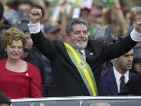 FILE - In this Jan. 1, 2003 file photo, Brazil's new President Luiz Inacio Lula da Silva holds his arms up as he rides in an open car with his wife Marisa after being sworn in as president, in Brasilia, Brazil. Silva's storybook rise from an impoverished childhood to the most popular president in the country's history before tumbling in a bribery scandal began in the northeastern Brazil state of Pernambuco, where he was the seventh of eight children. (AP Photo/Victor R. Caivano, File)