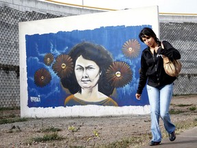 FILE - In this Jan. 31, 2017 file photo, a woman walks past a mural of slain environmentalist and indigenous leader Berta Caceres in Tegucigalpa, Honduras. Two European development banks financing construction of a controversial dam project in Honduras are pulling out following the murders of local activists including Caceres, a 2015 winner of the prestigious Goldman Environmental Prize.  (AP Photo/Fernando Antonio, File)