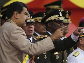 FILE - In this June 24, 2017 file photo, Venezuela's President Nicolas Maduro, left, talks to his Defense Minister Vladimir Padrino Lopez during Army Day celebrations at Fuerte Tiuna, in Caracas, Venezuela. Padrino Lopez challenged on Wednesday, July 19, 2017 the countries that have declared against the government's initiative to rewrite Venezuela's constitution, saying the nation will not submit to foreign governments. (AP Photo/Fernando Llano, File)