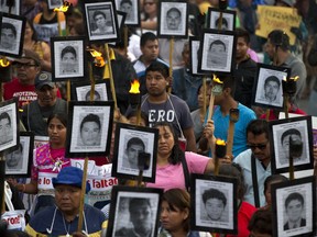 FILE - In this April 26, 2016 file photo, family members and supporters of 43 missing teachers college students from Guerrero state carry pictures of the missing students as they demand the case not be closed and that experts' recommendations about new leads be followed, in Mexico City. A report released Monday, July 10, 2017 by the internet watchdog group Citizen Lab found that targets of high-tech spying in Mexico included an international group of experts sent to the country by the Inter-American Human Rights Commission who had been critical of the government's investigation into the 2014 disappearance of the 43 students. (AP Photo/Rebecca Blackwell, File)