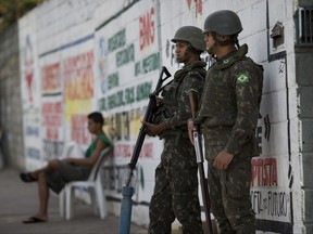 FILE - In this Feb. 14, 2017 file photo, soldiers guard the streets in Rio de Janeiro, Brazil. Brazil's Defense Minister Raul Jungmann promised Thursday, July 27, 2017 to have the military take an increasingly aggressive role in fighting drug trafficking in Rio de Janeiro. Jungmann said troops will not just patrol, man checkpoints and help recover caches of automatic weapons, but also be used in police operations against drug traffickers. (AP Photo/Silvia Izquierdo, File)