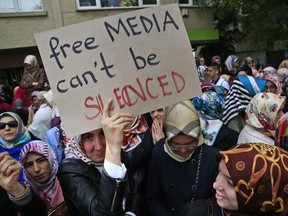 FILE - In this Wednesday Oct. 28, 2015 file photo, protesters holding placards demonstrate across the street from the headquarters of a media company that owns opposition television stations Bugun TV and Kanal Turk, the Bugun and Millet newspapers and other business interests, after being seized by the government, in Istanbul. Many feel the full force of the Turkish government's wrath against press critical of Turkey's President Recep Tayyip Erdogan, particularly after July 2016's failed coup attempt and ensuing crackdown. About 160 journalists are currently in jail, mostly on terrorism-related charges, while more than 150 media outlets, from broadcasters to newspapers and magazines, have been shut down, leaving thousands unemployed. (AP Photo/Lefteris Pitarakis, File)