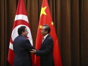 Tunisia's Foreign Minister Khemaies Jhinaoui, left, and China's Foreign Minister Wang Yi, right, shake hands as they pose for a photo before a meeting at the Ministry of Foreign Affairs in Beijing, Wednesday, July 19, 2017. (AP Photo/Mark Schiefelbein, Pool)
