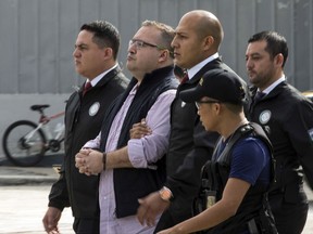 Mexico's ex-governor of Veracruz state, Javier Duarte, is escorted in handcuffs by police to an aircraft as he is extradited to Mexico City, at an Air Force base in Guatemala City, Monday, July 17, 2017. Duarte faces charges of embezzlement and ties to organized crime in his home country. (AP Photo/Moises Castillo)