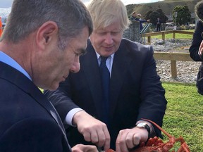 New Zealand's Minister for Primary Industries Nathan Guy, left, and British Foreign Secretary Boris Johnson, right,  share a plate of crayfish at Kaikoura, New Zealand, Monday, July 24, 2017. Johnson is in the South Pacific nation for two day visit as Britain looks to strengthen its ties with its former colony amid a broader reshaping of Britain's global relationships as it prepares to leave the European Union. (Corin Dann/Pool via AP)