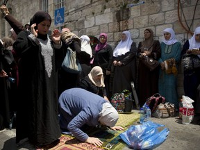 Palestinian women pray at the Lion's Gate following an appeal from clerics to pray in the streets instead of the Al Aqsa Mosque compound, in Jerusalem's Old City, Tuesday, July 25, 2017. Dozens of Muslims have prayed in the street outside a major Jerusalem shrine, heeding a call by clerics not to enter the site until a dispute with Israel over security arrangements is settled. This comes after Israel removed metal detectors earlier on Tuesday. (AP Photo/Oded Balilty)