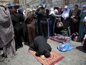 Palestinians women pray at the Lion's Gate following an appeal from clerics to pray in the streets instead of inside the Al Aqsa Mosque compound, in Jerusalem's Old City, Tuesday, July 25, 2017. Dozens of Muslims have prayed in the street outside a major Jerusalem shrine, heeding a call by clerics not to enter the site until a dispute with Israel over security arrangements is settled. This comes after Israel removed metal detectors earlier on Tuesday. (AP Photo/Oded Balilty)