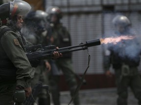 A Bolivarian National Guard officer fires tear gas canister aimed at anti-government protesters marching to the Supreme Court to support new magistrates named to the government-dominated Supreme Court by opposition-led led National Assembly, in Caracas, Venezuela, Saturday, July 22, 2017. (AP Photo/Fernando Llano)