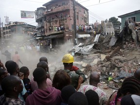 Onlookers watch as rescue workers search for survivors at the rubbles of a collapsed building in a densely populated neighborhood in Lagos, Nigeria Tuesday, July 25, 2017. Rescue work is still ongoing. (AP Photo/Sunday Alamba)