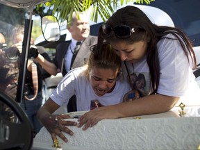 Adriana Maria dos Santos, right, mother of late Vanessa do Santos, and a friend Laisa, cry over Vanessa's casket during her burial in Rio de Janeiro, Brazil, Thursday, July 6, 2017. The 10-year-old child was killed two days earlier after being hit in the head by a stray bullet in her home during a police operation in the Lins complex of favela. (AP Photo/Silvia Izquierdo)