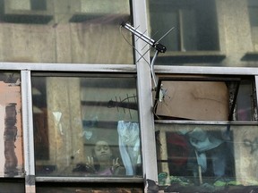 In this June 24, 2017 photo, a girl looks out from her window at the former Federal Police headquarters building in downtown Sao Paulo, Brazil. Around 350 families live in the building that originally was the headquarters of the Federal Police. Fair-housing groups now occupy about 80 previously empty properties downtown, some for as long as a decade, according to the city's Housing Department. (AP Photo/Andre Penner)