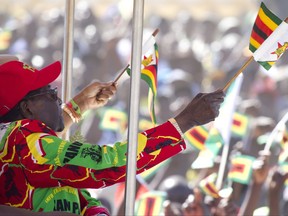 Zimbabwe President Robert Mugabe waves the Zimbabwean flag while greeting the crowd at a rally in Lupane about 170 Kilometres north of Bulawayo, Friday, July, 21, 2017. Mugabe's rally is his first since his return from a routine medical review in Singapore. The world's oldest leader has launched a series of rallies targeting the youth ahead of Presidential elections set for 2018. (AP Photo/Tsvangirayi Mukwazhi)
