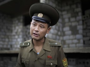 In this Friday, July 21, 2017, photo, Maj. Jong Il Hyon, 44, a member of a bomb squad for South Hamgyong, speaks to The Associated Press at a construction site on the outskirts of Hamhung, North Korea's second-largest city, where workers unearthed a rusted but still potentially deadly mortar round in February. Over the years, Maj. Jong Il Hyon, a 10-year veteran, has lost five colleagues to explosions. He carries a lighter one gave him before he died. He also bears a scar on his left cheek from a bomb disposal mission gone wrong. (AP Photo/Wong Maye-E)