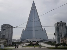 In this Friday, July 28, 2017, photo, people walk past the 105-story pyramid shaped Ryugyong Hotel in Pyongyang, North Korea.
