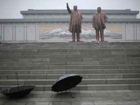 Umbrellas are left at the bottom of the stairs as people pay their respects and lay flowers at the foot of giant bronze statues of their late leaders Kim Il Sung and Kim Jong Il at Munsu Hill on Thursday, July 27, 2017, in Pyongyang, North Korea as part of celebrations for the 64th anniversary of the armistice that ended the Korean War. (AP Photo/Wong Maye-E)