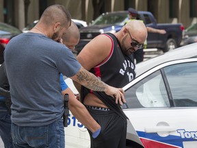 Police search a man in handcuffs who was driving Lamborghini that they pulled over at the intersection of Bloor Street and Ted Rogers Way in Toronto, Ontario, August 14, 2017. Traffic in the area was snarled as the cops hesitated to move the pricey car.