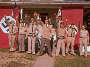 George Lincoln Rockwell (centre), self-styled head of the American Nazi Party, standing with group of followers in uniform with Nazi and American flags.