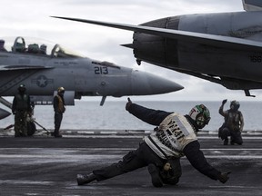 A Landing Signal Officer (White Shirt) signals to a pilot preparing for take off during joint military exercise, Saxon Warrior, aboard the USS George H.W. Bush on August 6, 2017 off the north west coast of the United Kingdom.