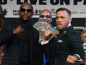 Floyd Mayweather Jr., and Conor McGregor pose at a news conference WEdnesday to further hype Saturday's fight between them in Las Vegas.