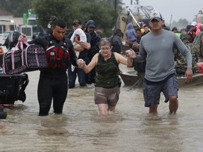 An evacuee is helped to dry land after her home was inundated with flooding from Hurricane Harvey on Aug. 28, 2017 in Houston, Texas.