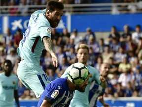 FC Barcelona's Lionel Messi, left, heads the ball beside Deportivo Alaves' Alfonso Pedraza during the Spanish La Liga soccer match between FC Barcelona and Deportivo Alaves, at Mendizorroza stadium, in Vitoria, northern Spain, Saturday, Aug. 26, 2017. (AP Photo/Alvaro Barrientos)