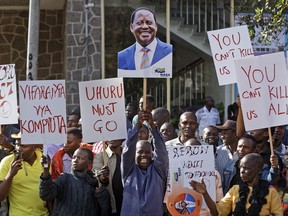 A supporter of main opposition leader Raila Odinga holds a placard of his face, center, as they make a small demonstration outside the Supreme Court in Nairobi, Kenya, Friday, Aug. 18, 2017.  Dozens of supporters gathered in front of the court building where opposition lawyers were expected to file a petition contesting President Uhuru Kenyatta's re-election. (AP Photo/Ben Curtis)