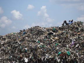 FILE - In this Thursday, Nov. 12, 2015 file photo, a man who scavenges for a living takes a rest next to a Marabou stork on top of a mountain of garbage and plastic bags at the dump in the Dandora slum of Nairobi, Kenya. A ban on plastic bags came into force in Kenya Monday, Aug. 28, 2017 and those found violating the new regulation could receive large fines or jail terms. (AP Photo/Ben Curtis, File)
