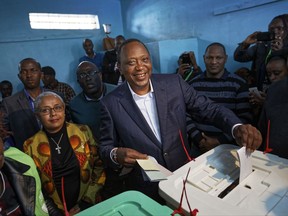 Kenya's President Uhuru Kenyatta casts his vote, accompanied by his wife Margaret, center-left, in Gatundu, north of Nairobi, in Kenya Tuesday, Aug. 8, 2017. Kenyans are going to the polls to vote in a general election after a tightly-fought presidential race between incumbent President Uhuru Kenyatta and main opposition leader Raila Odinga. (AP Photo/Ben Curtis)