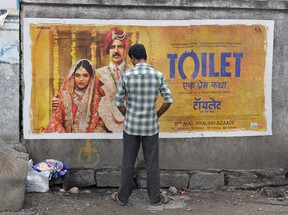 An Indian man urinates on a wall on the roadside in front of a poster for the Hindi film Toilet in Hyderabad on August 12, 2017. The Bollywood film Toilet: Ek Prem Katha (Toilet: A Love Story) is inspired by the true-life tale of one man's battle to build toilets in his village in rural India.