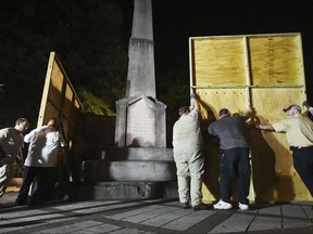 Birmingham city workers use plywood panels to cover the Confederate Monument in Linn Park, in Birmingham, Ala., Tuesday night, Aug. 15, 2017, on orders from Mayor William Bell. (Joe Songer  /AL.com via AP)