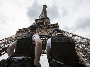 FILE- In this Friday, June 10, 2016 file photo, French riot police officers patrol under the Eiffel Tower, in Paris. A young French man who recently was discharged from a psychiatric hospital is under investigation for glorifying terrorism after he brandished a knife and tried to breach security at the Eiffel Tower, authorities said Sunday, Aug. 6, 2017. (AP Photo/Kamil Zihnioglu, File)