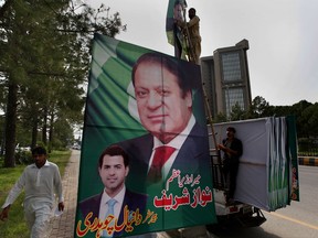 Pakistani workers install a huge billboard of deposed Prime Minister Nawaz Sharif on the planned route of his rally at a highway in Islamabad, Pakistan, Tuesday, Aug. 8, 2017. According to Malik Mohammad Ahmed, a spokesman in Punjab where Lahore is the provincial capital, Sharif planned to travel with a convoy of supporters by road on Wednesday from the capital, Islamabad, to Lahore. (AP Photo/ Anjum Naveed)