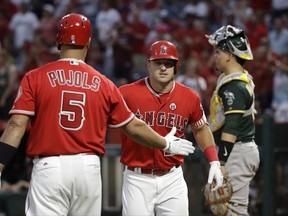 Los Angeles Angels' Mike Trout, center, celebrates his home run with Albert Pujols during the first inning of a baseball game against the Oakland Athletics, Wednesday, Aug. 30, 2017, in Anaheim, Calif. (AP Photo/Jae C. Hong)