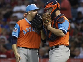 Houston Astros starting pitcher Collin McHugh, left, chats with catcher Evan Gattis during the first inning of a baseball game against the Los Angeles Angels, Friday, Aug. 25, 2017, in Anaheim, Calif. (AP Photo/Jae C. Hong)