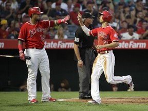 Los Angeles Angels' Andrelton Simmons, right, high-fives Martin Maldonado after he scored on a single hit by C.J. Cron during the second inning of a baseball game against the Baltimore Orioles, Tuesday, Aug. 8, 2017, in Anaheim, Calif. (AP Photo/Jae C. Hong)